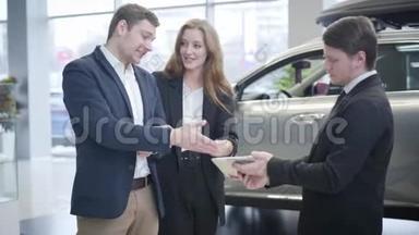 年轻的高加索人成功地选择了汽车经销商的<strong>新</strong>车。 微笑的男人和女人谈论销售